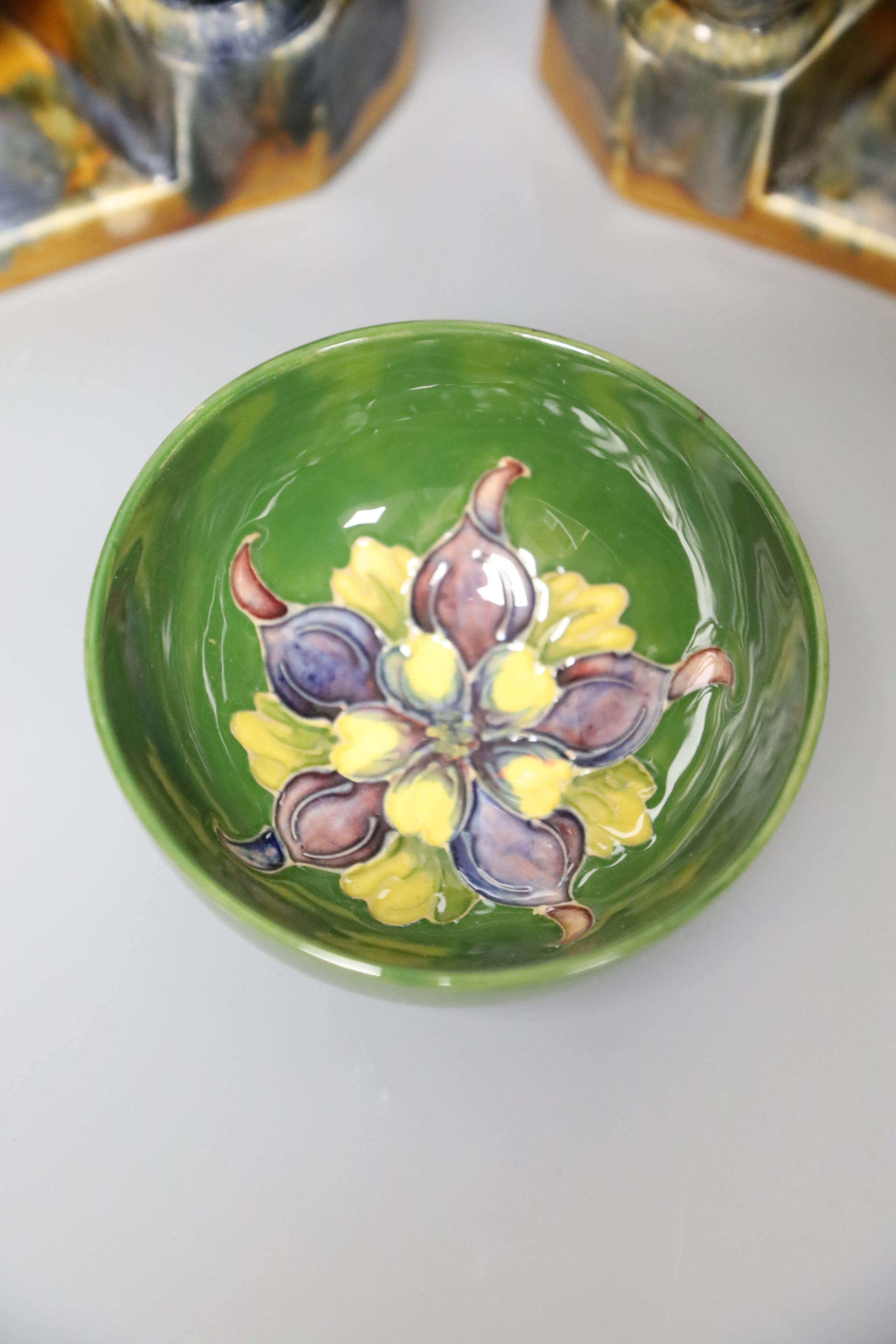 A Moorcroft green ground 'Columbine' pattern bowl, Dia 11cm and two pairs of ceramic bookends,